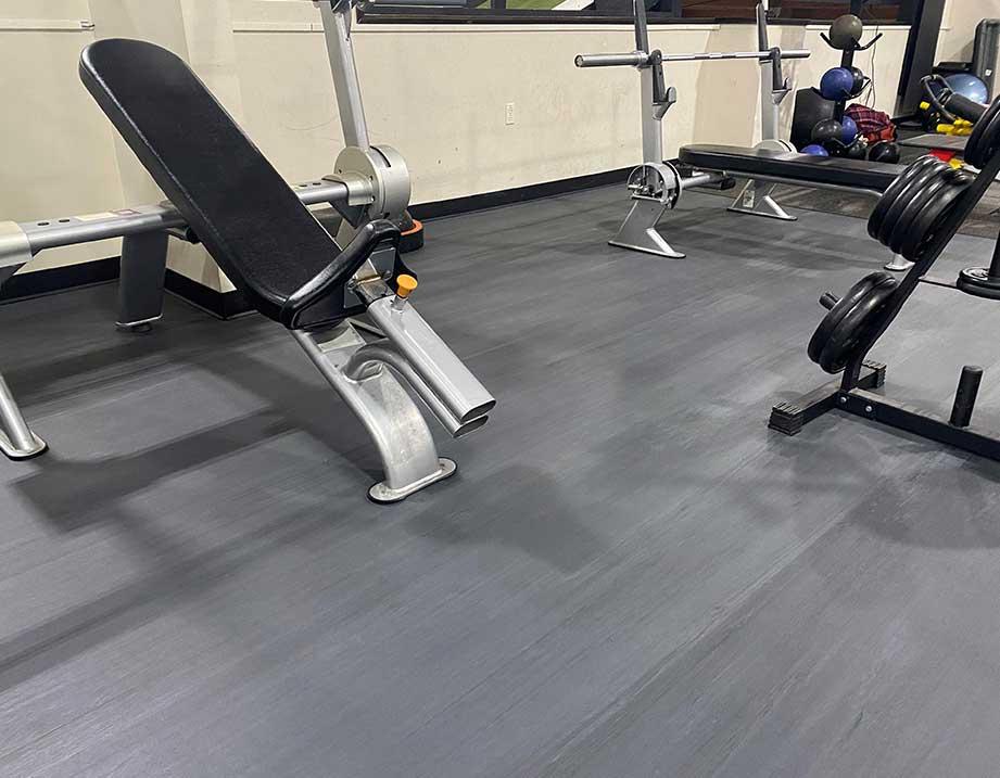 Adjustable gym benches near a barbell setup in a fitness space.