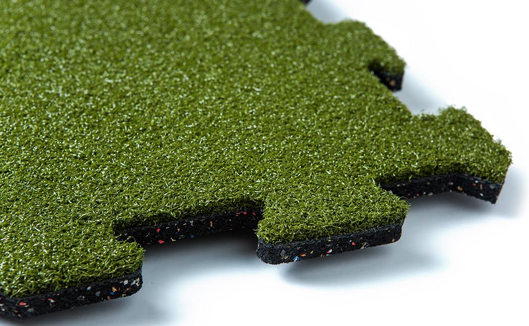 An Ecore flooring sample of Vulcanized Composition Rubber that is fusion bonded to a turf surface.