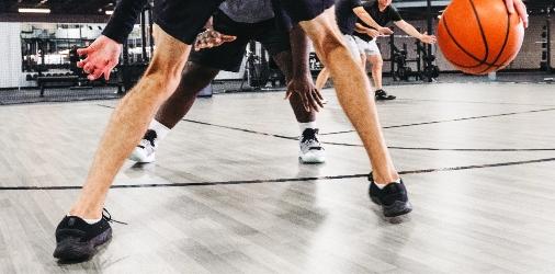 Close-up of basketball players' legs and hands during a game, showing intense movement and competition.